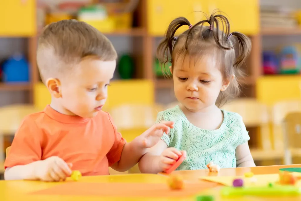 Toddlers Boy and Girl Playing at Table with Educational Toys
