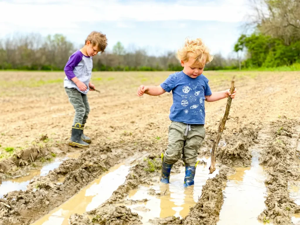 Two Boys Wearing Boots in the Mud 